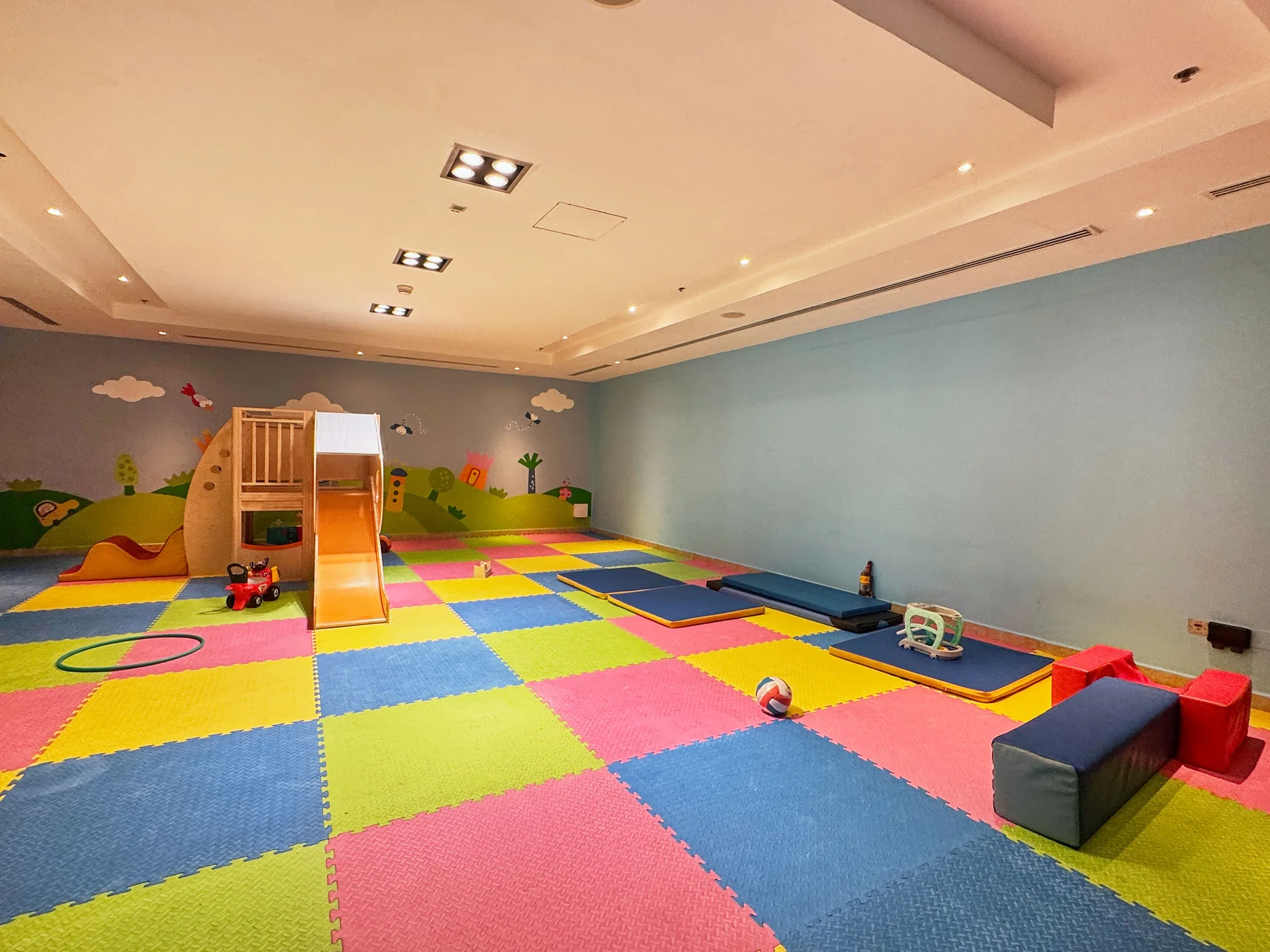 Una colorida sala de juegos tiene una estructura para trepar y un suelo de losetas acolchadas.