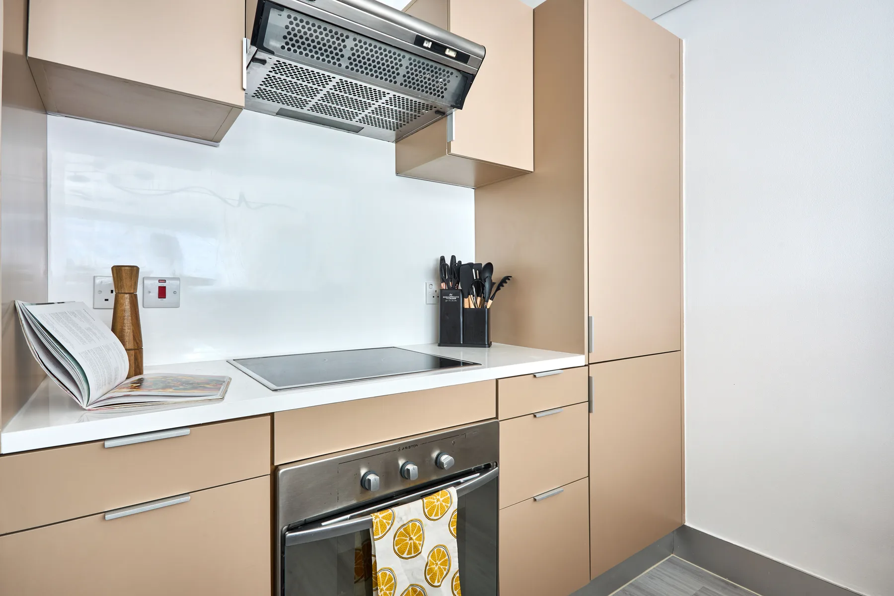 Una cocina moderna con placa de cocción, horno y armarios de tonos claros.