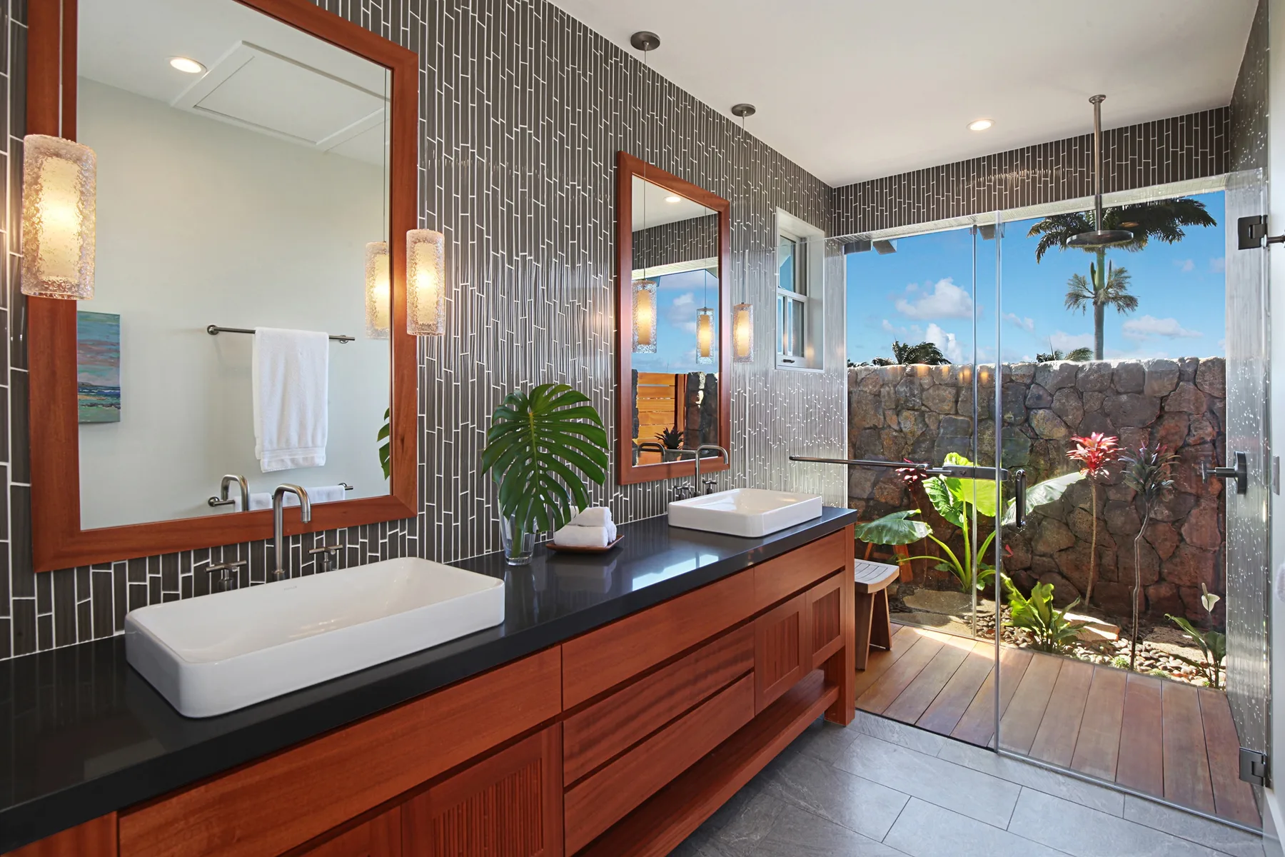 A bathroom vanity with a vessel sink faces glass doors opening onto a garden.