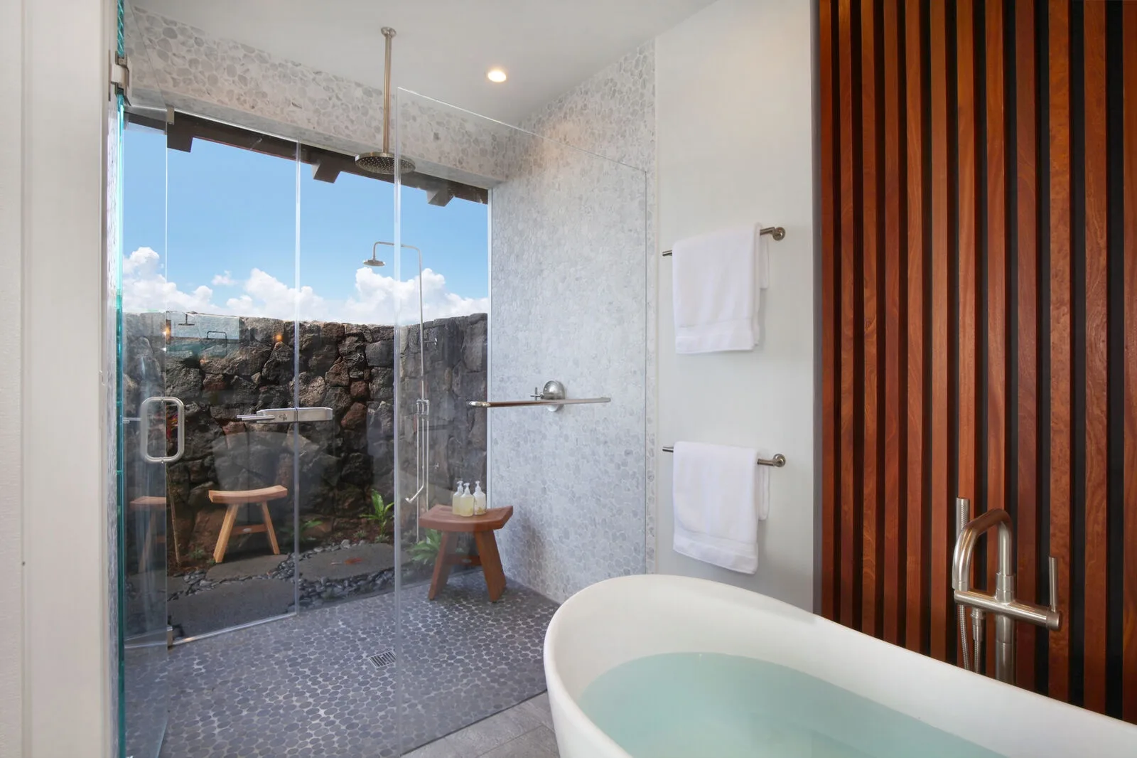 A bathroom with a bathtub and glass shower beside a window.