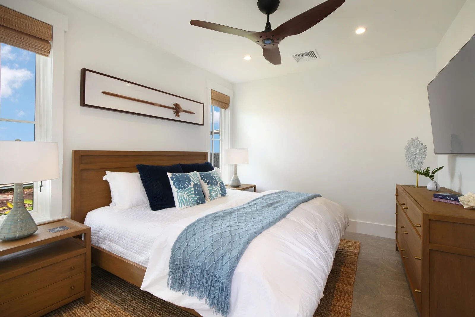 A bedroom with a neatly made bed and a blue throw.