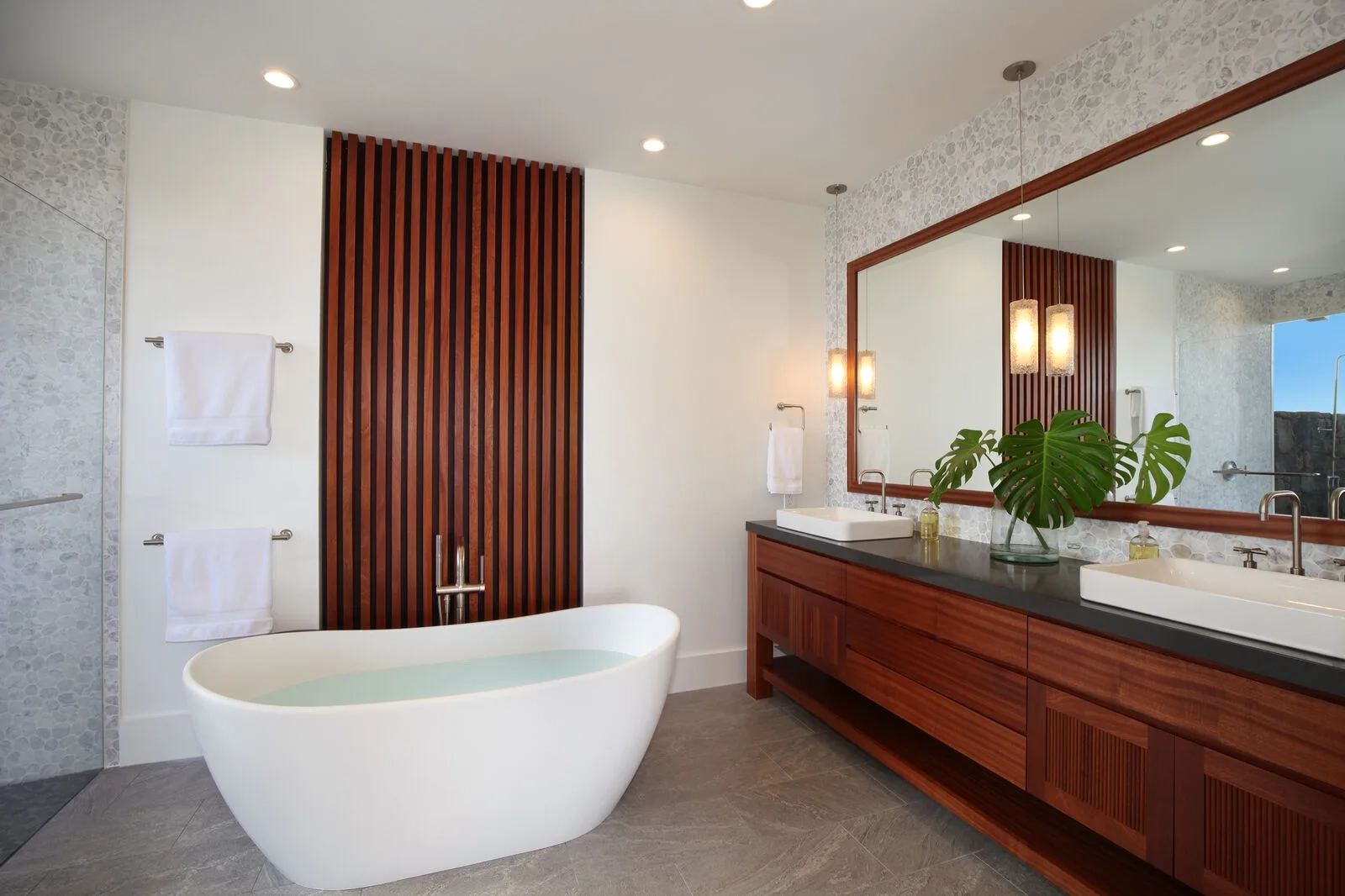 A bathroom with a freestanding tub and a long vanity beneath a large mirror.