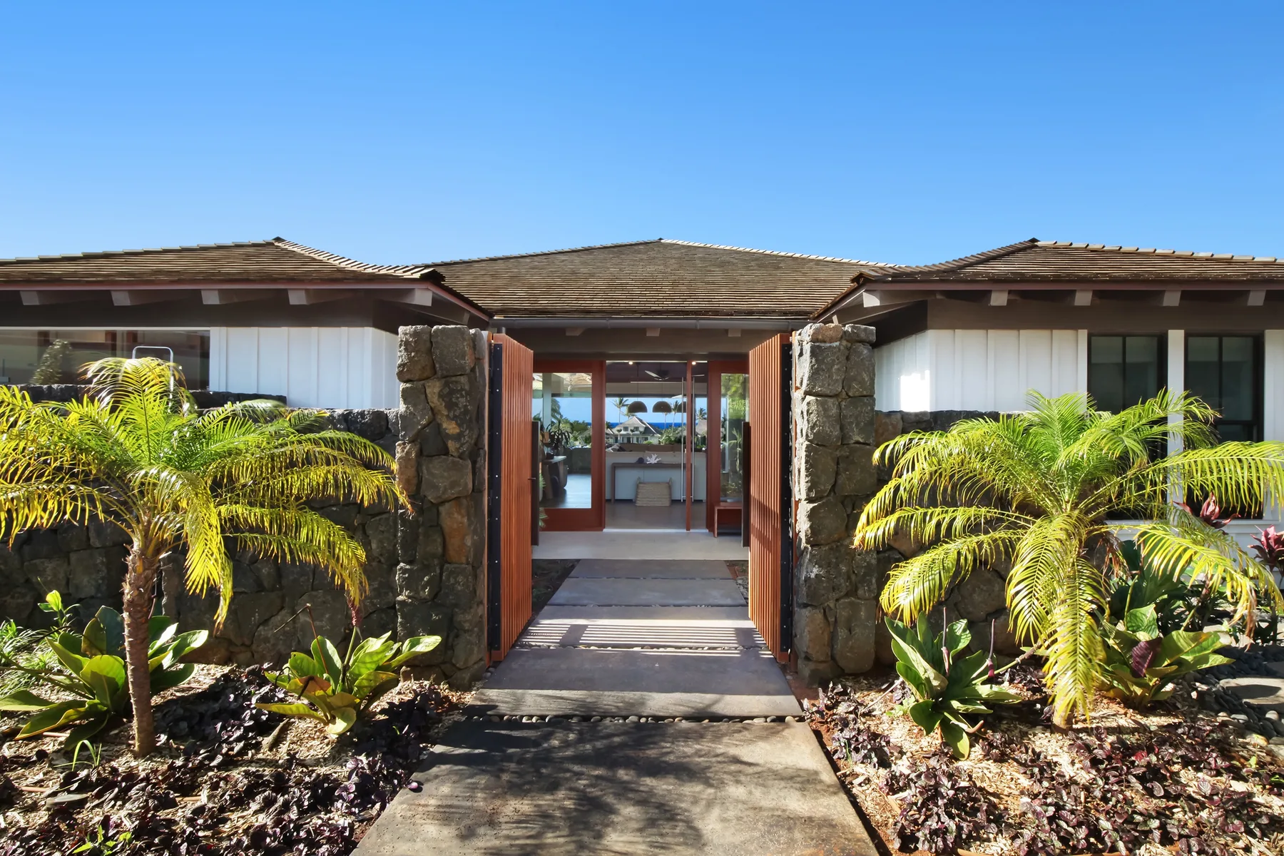 A low building has a stone-framed entrance opening onto a paved walkway.