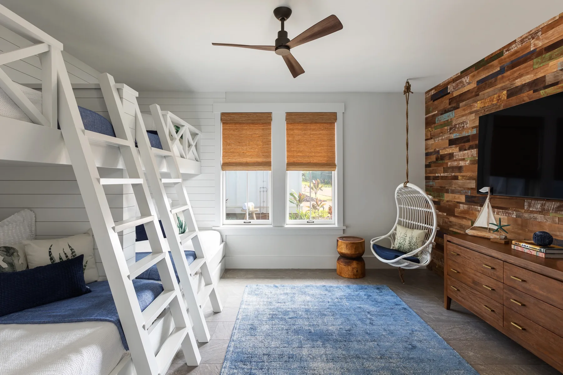 A bedroom with white bunk beds, two windows, and a blue rug.