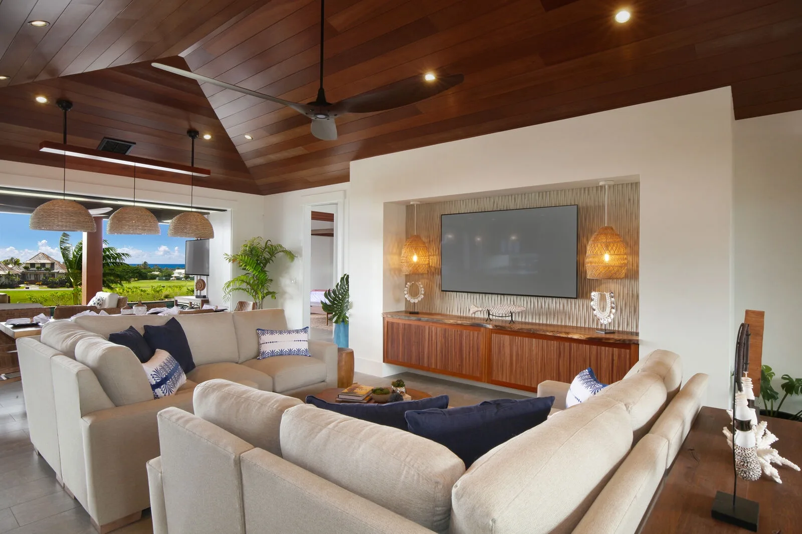 A spacious living room with pale seating arranged around a television and wooden cabinet.