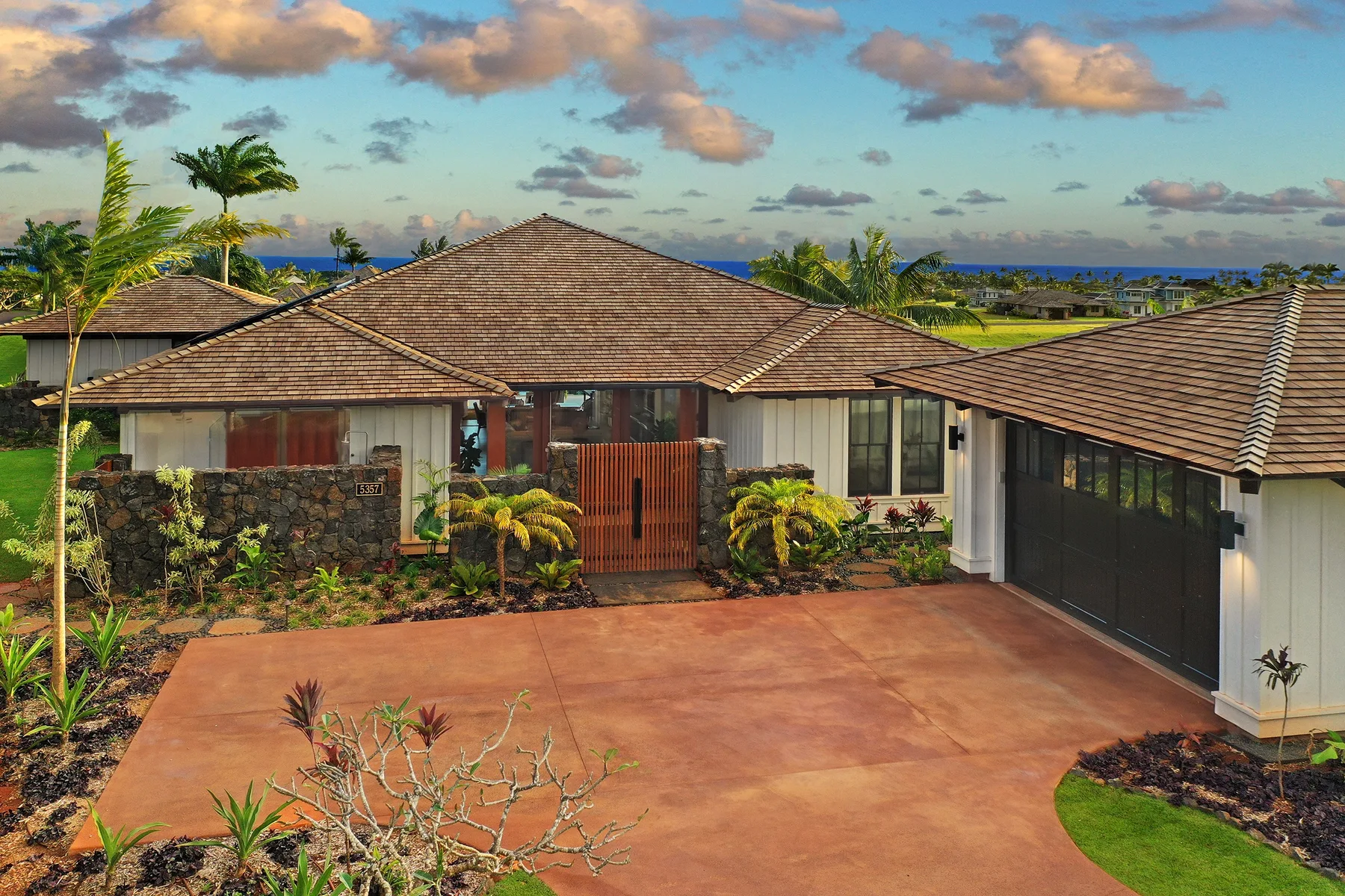 A single-story house with a tiled roof faces a wide paved driveway.