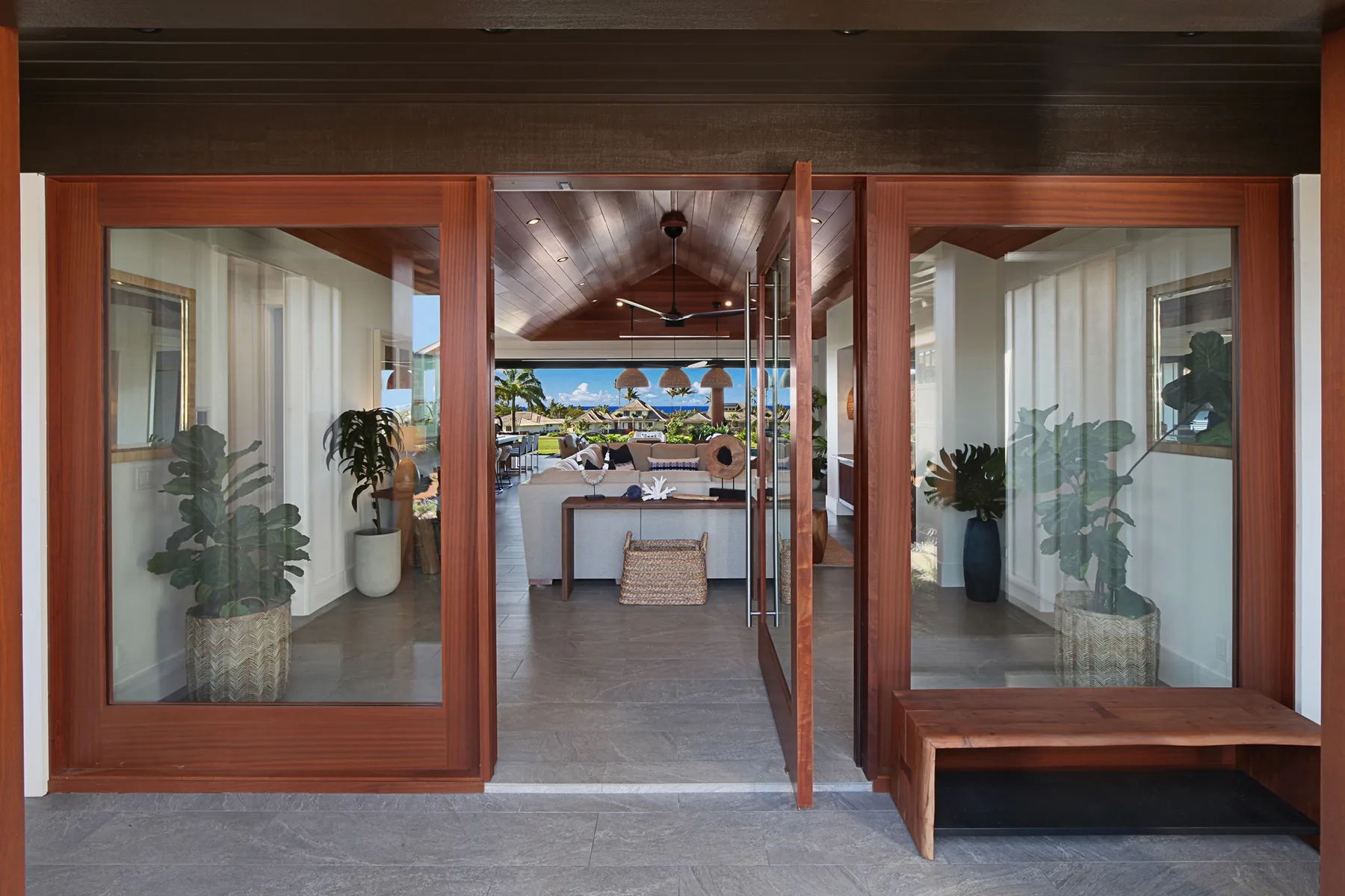 A glass-fronted entrance opens onto a bright interior with plants and a view beyond.