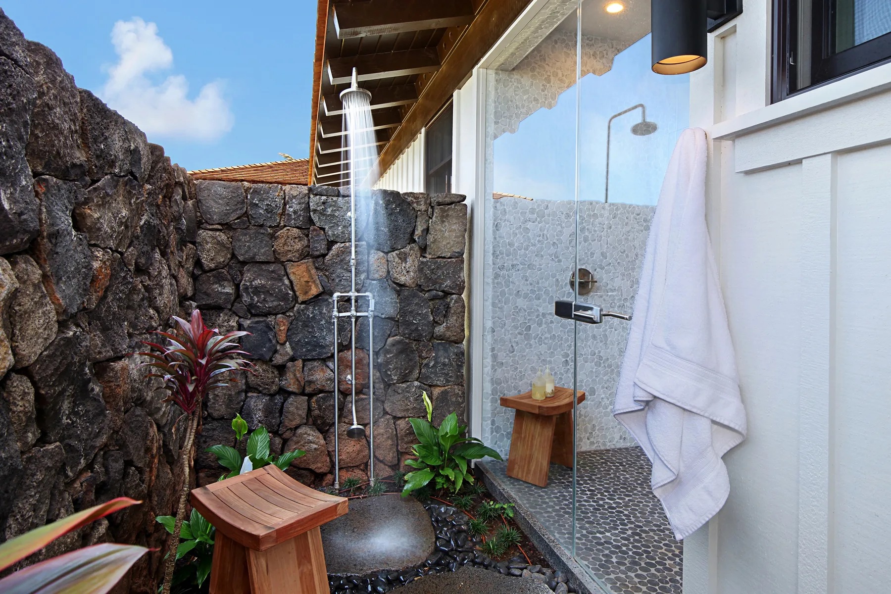 An outdoor shower area with a glass partition and stone walls.