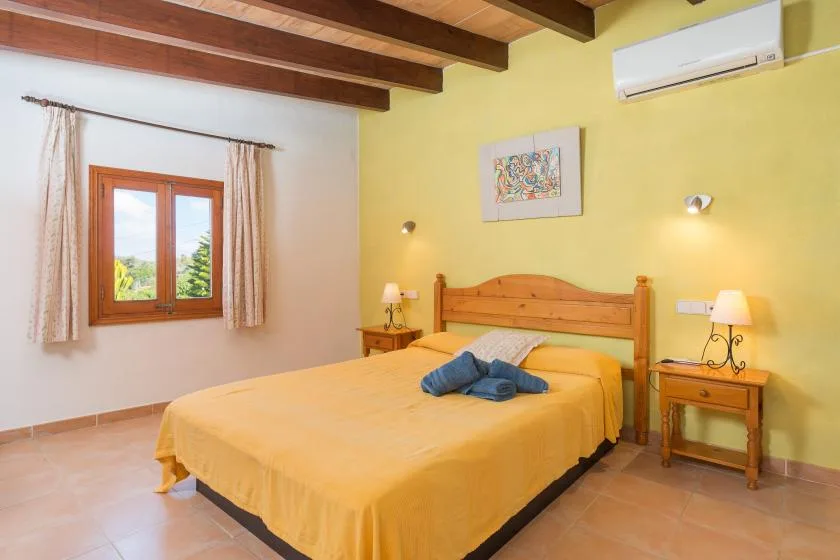 A bedroom with a wooden bed, yellow bedding, and a window.