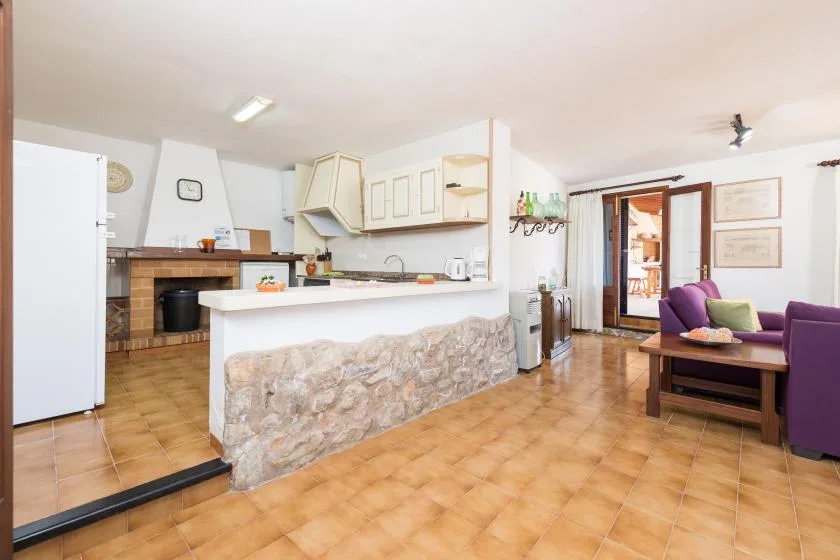 An open kitchen and living area with a stone-faced counter and purple seating.