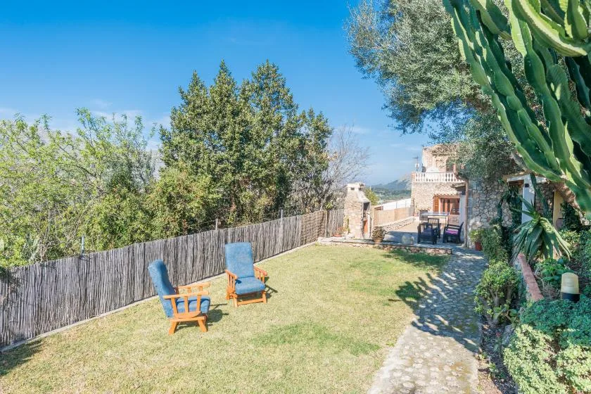 A sunny garden with outdoor seating, a stone path, and a house in the background.