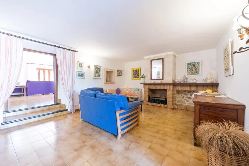 A living room with blue seating, a fireplace, and a tiled floor.
