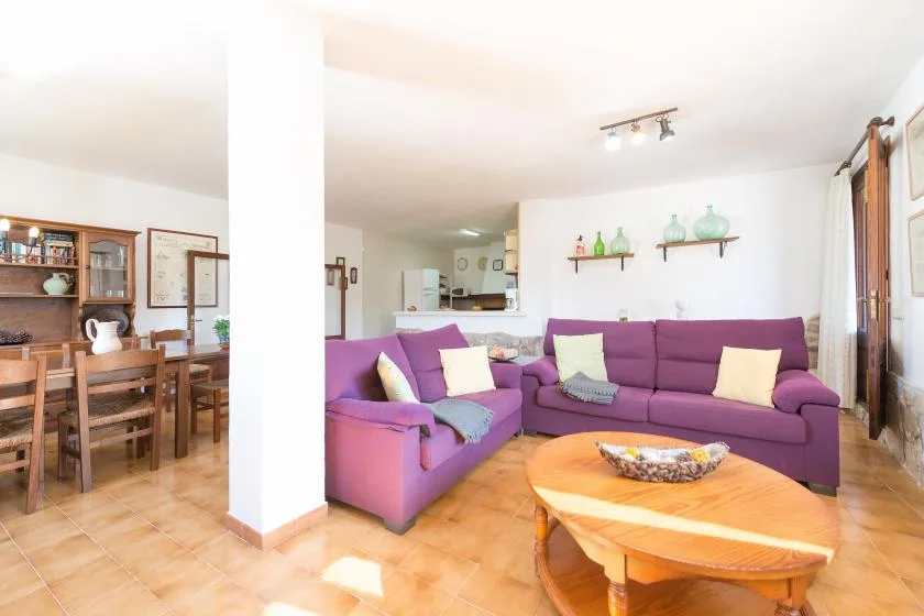 A bright living room with purple seating and a wooden coffee table.