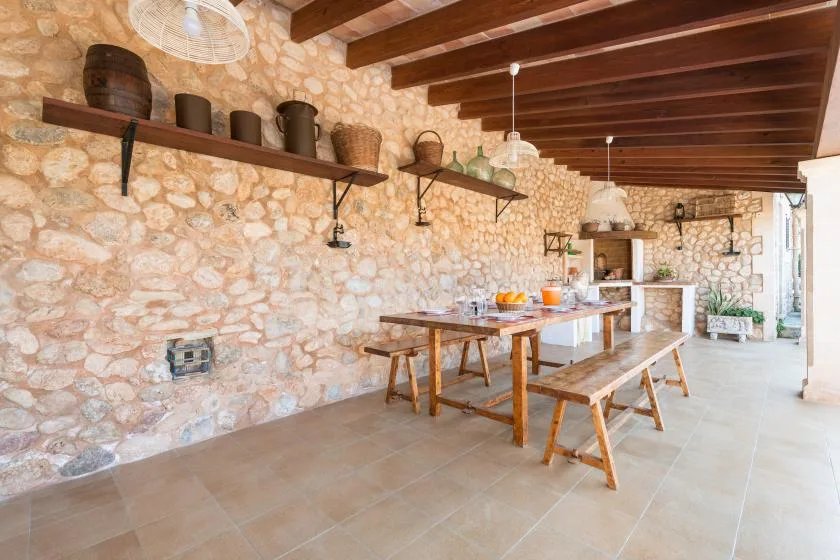 A rustic dining area with a long wooden table beneath exposed ceiling beams.