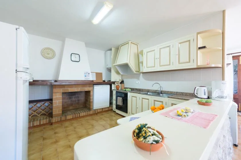 A kitchen with pale cabinets, a countertop, and a brick fireplace.
