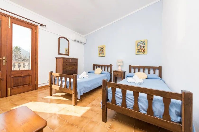 A bedroom with two wooden beds and a wooden door opening onto a balcony.