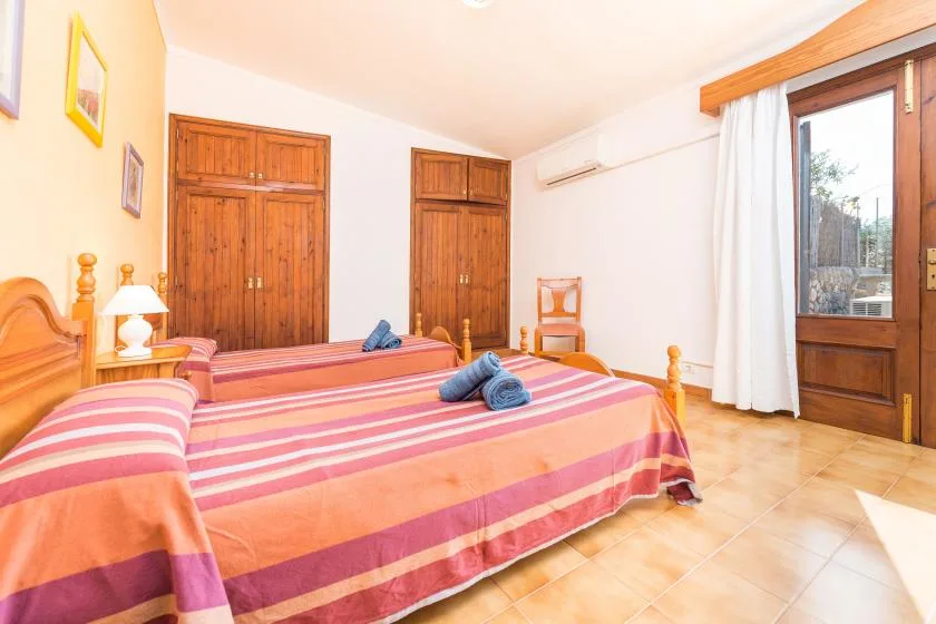 A bedroom with two beds and a glass door opening onto a view outside.