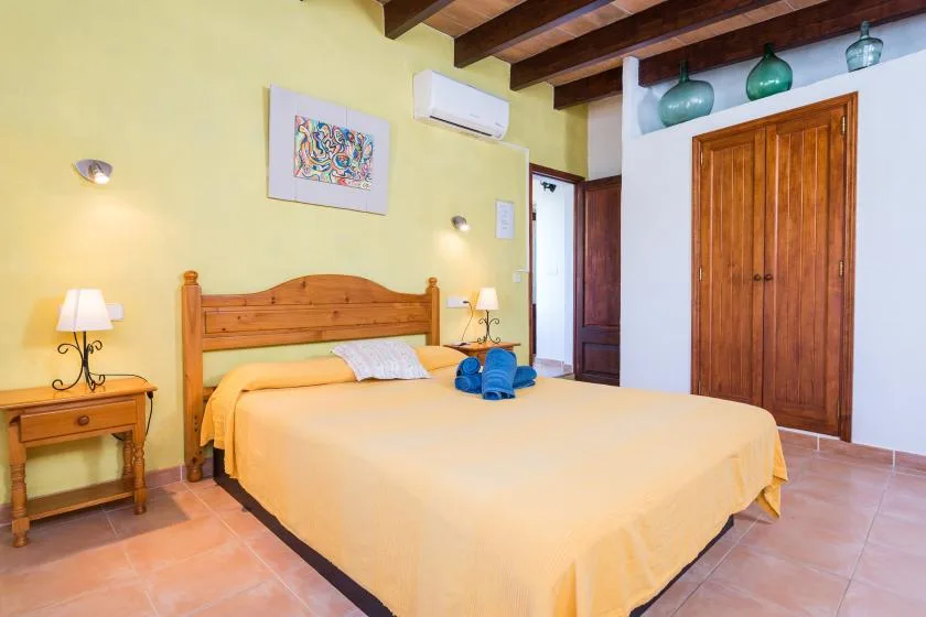 A bedroom with a wooden bed, pale yellow bedding, and matching bedside tables.
