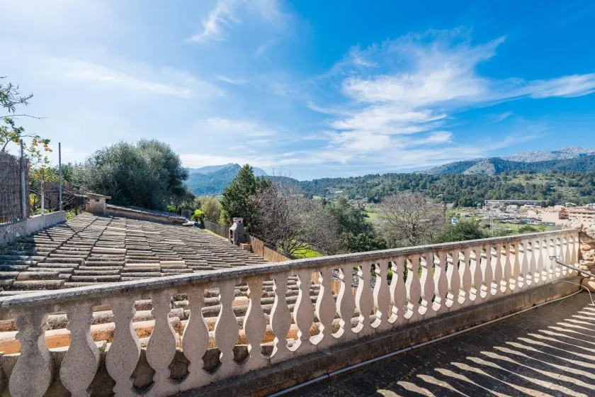 A rooftop terrace overlooks a wooded valley and distant hills.