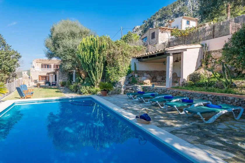 An outdoor swimming pool with lounge seating beside a hillside property.
