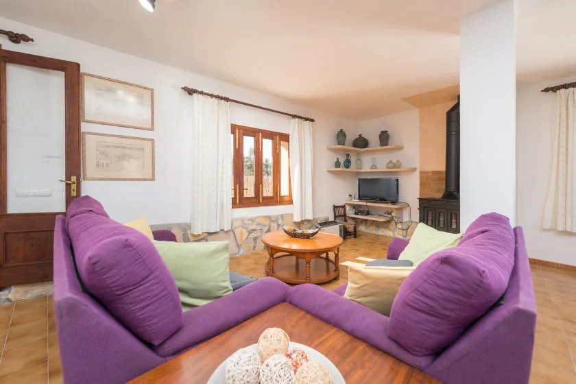 A living room with purple seating arranged around a wooden coffee table.
