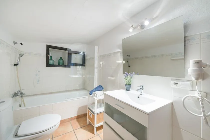A bright bathroom with a bathtub, toilet, and sink beneath a large mirror.