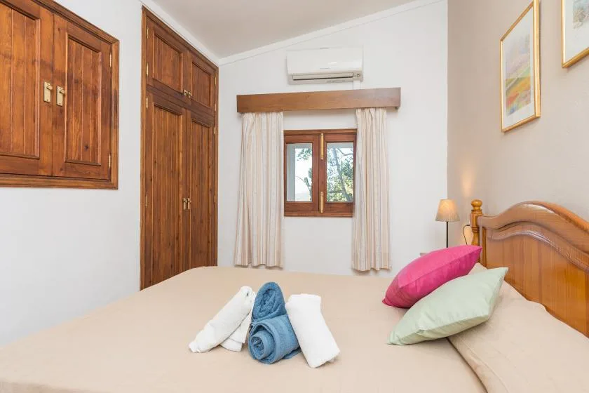 A bedroom with a wooden bed and a window framed by curtains.