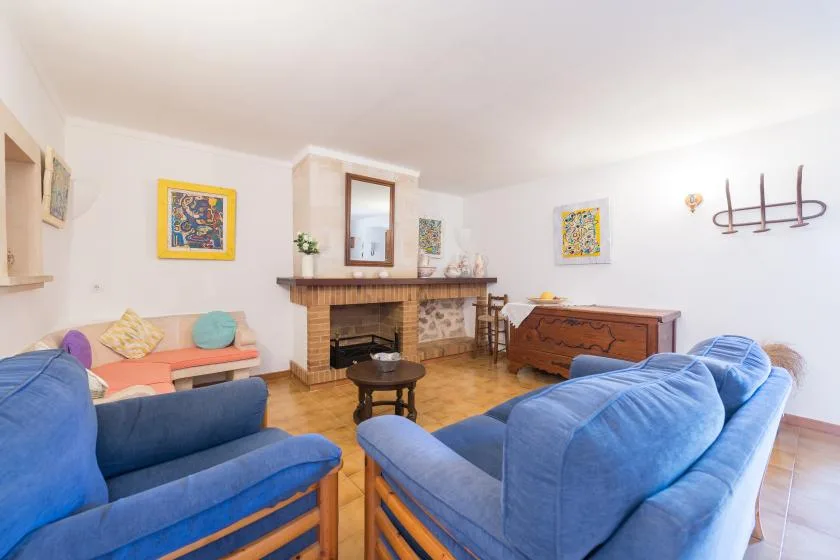 A living room with blue seating, colorful wall art, and a fireplace.
