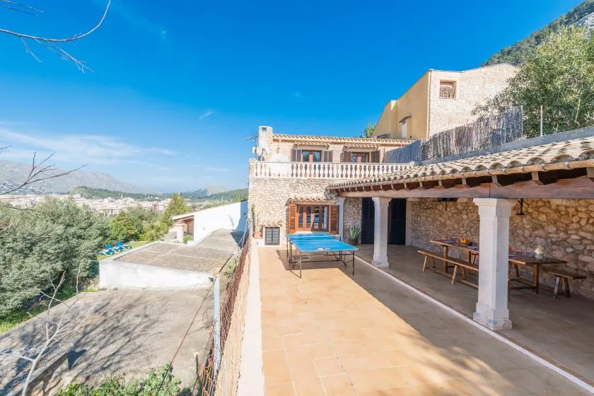 A tiled terrace beside a stone building overlooks a green valley and distant hills.