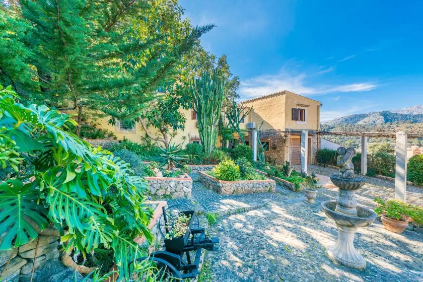 A landscaped garden patio with a stone fountain and surrounding greenery.