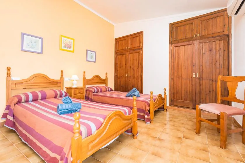 A bedroom with two beds, colorful striped bedding, and wooden wardrobes.