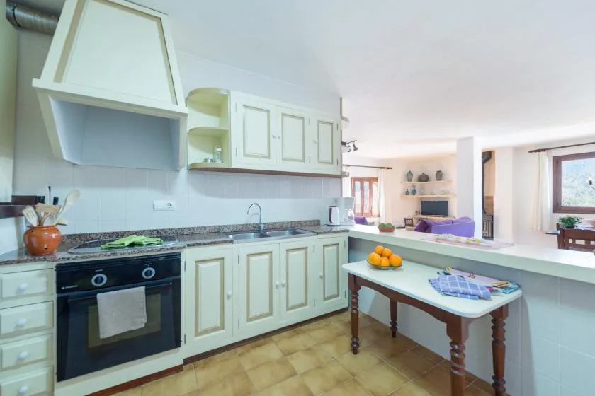 A bright kitchen with pale cabinets, a dark countertop, and a small table.