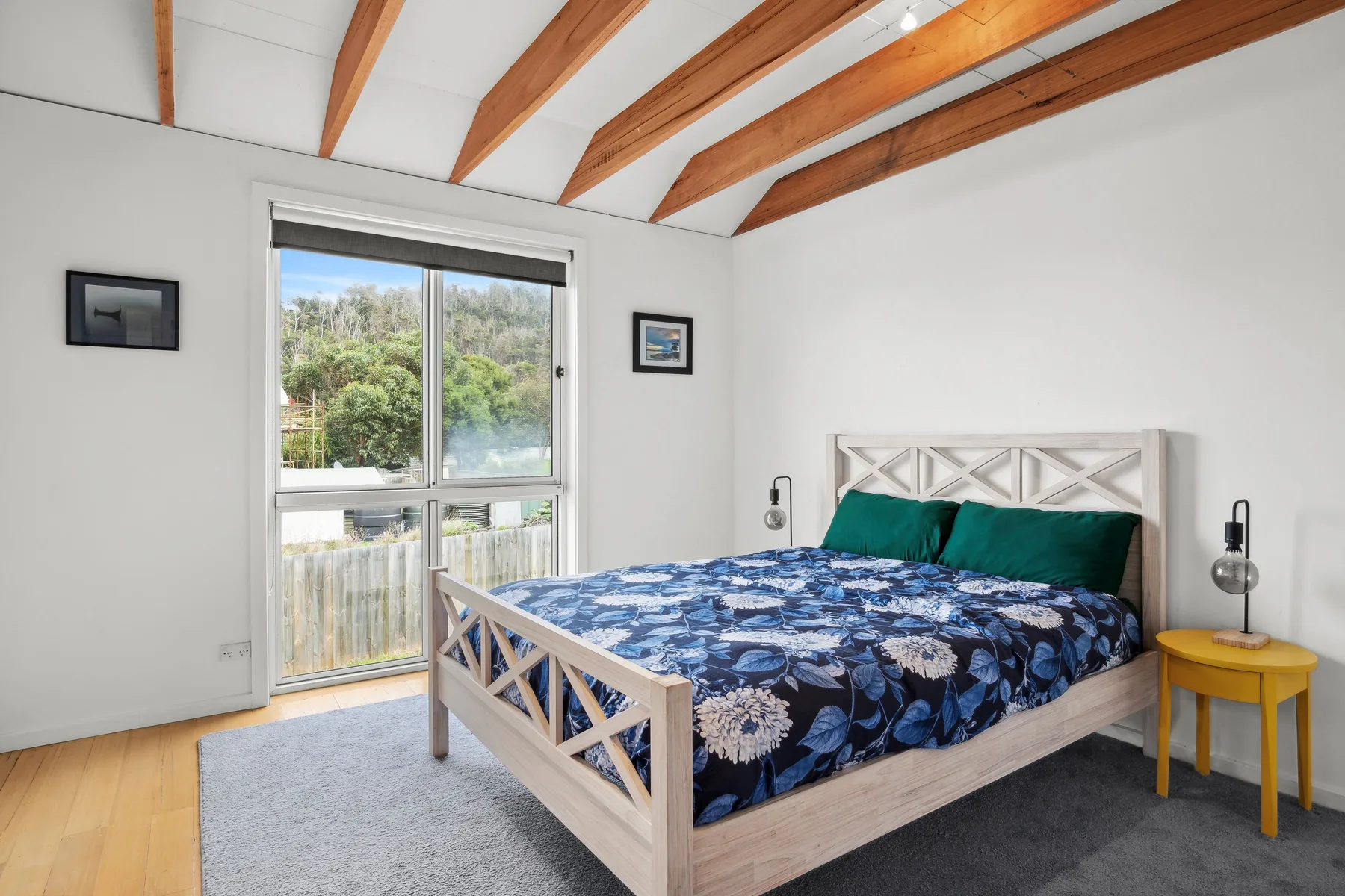 Un dormitorio con una cama bajo vigas de madera expuestas.
