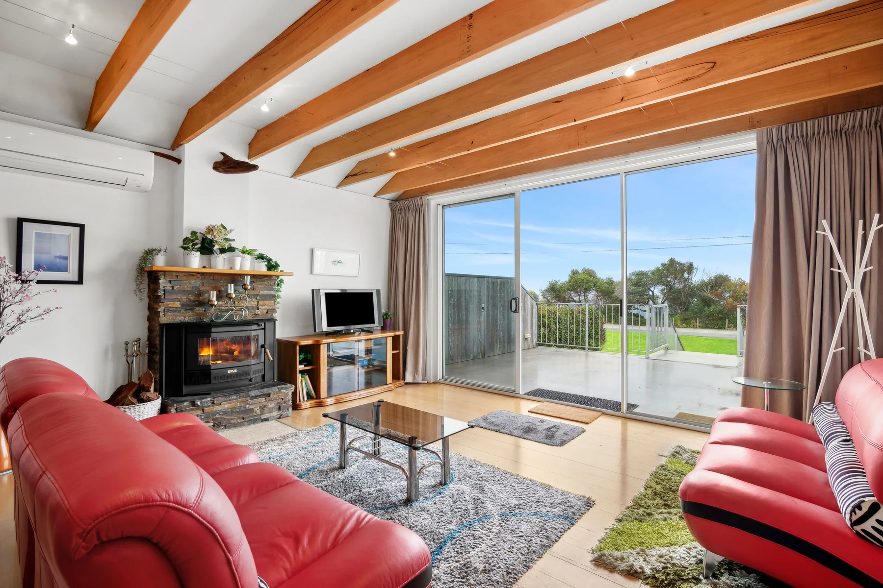 Sala de estar con asientos, chimenea y puertas corredizas de vidrio que dan a un patio.