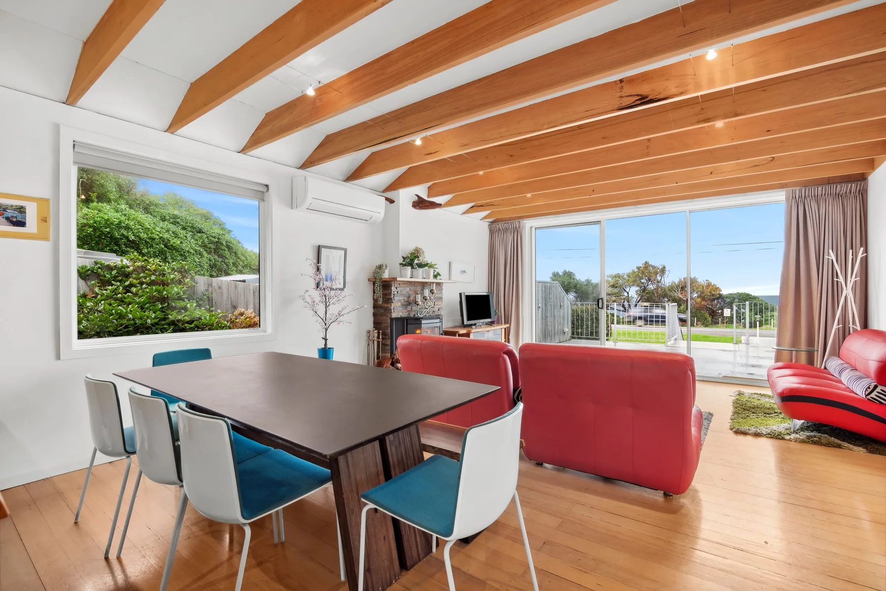 Una zona de estar y comedor con asientos rojos junto a grandes ventanas.