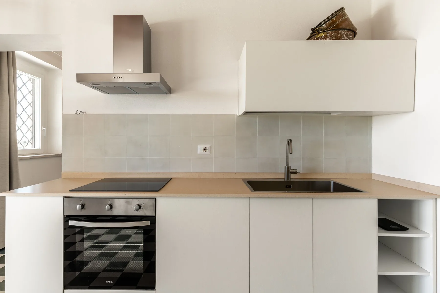 Una cocina moderna con gabinetes blancos, placa de cocción, horno y fregadero.