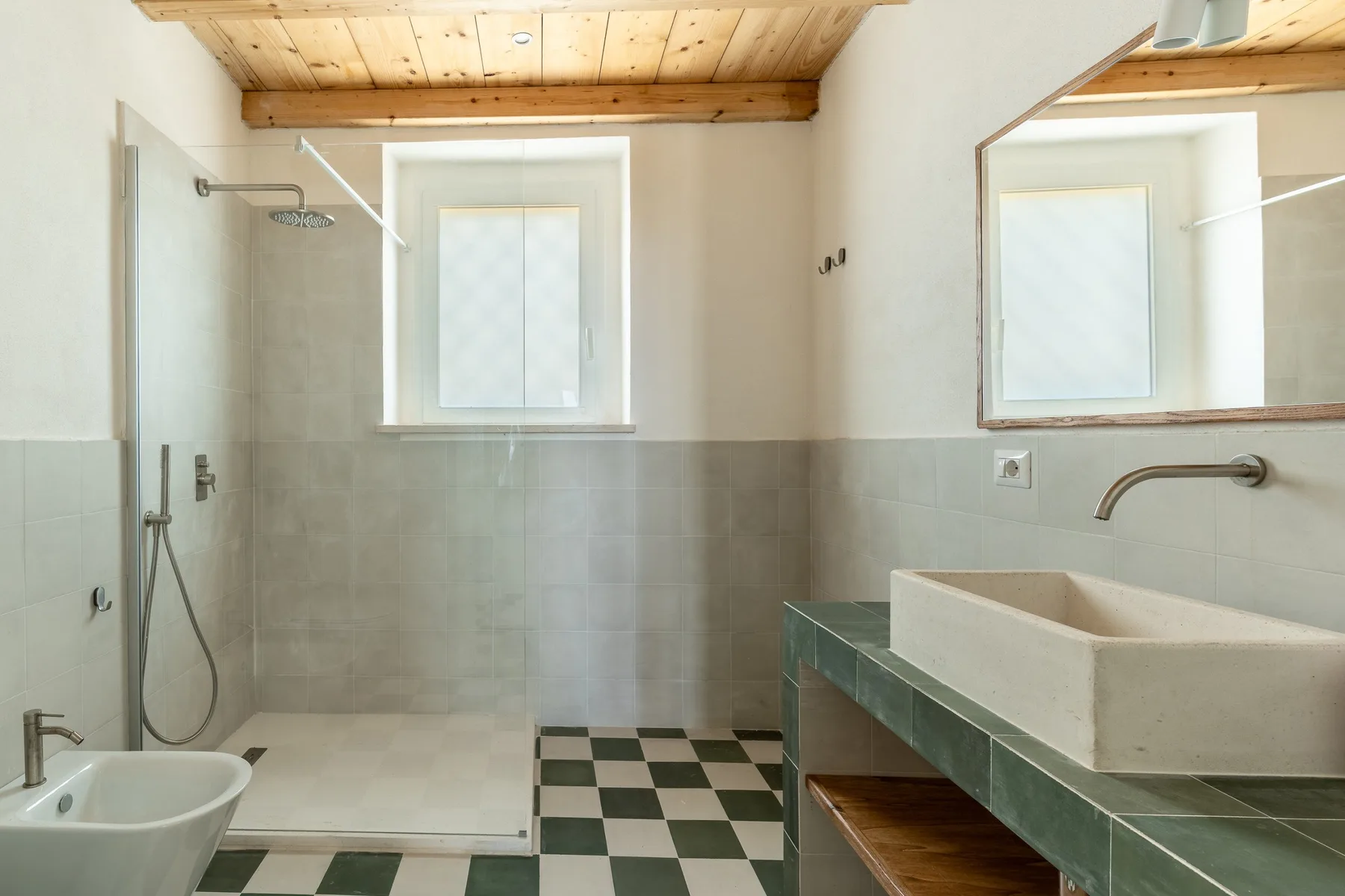 Un baño con azulejos, ducha, lavabo y un espejo grande.