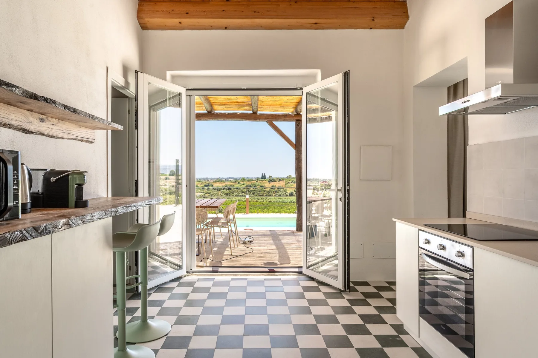 Una cocina luminosa se abre a una terraza exterior mediante puertas de vidrio.