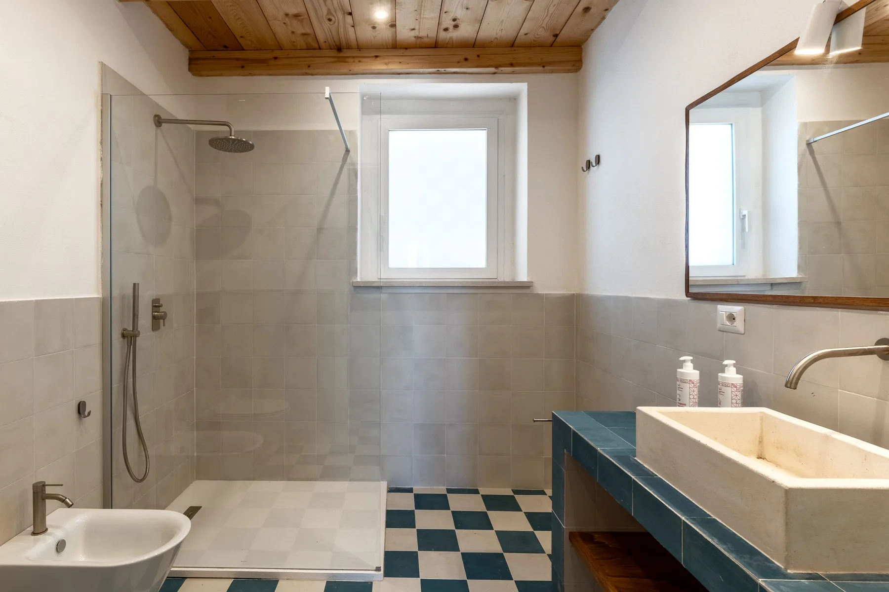 Un baño con ducha de vidrio, lavabo y una ventana.