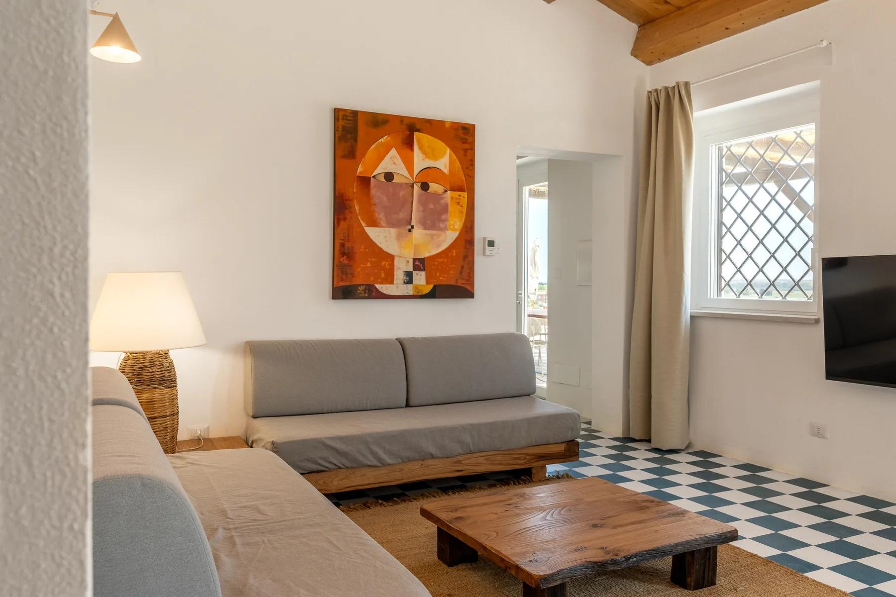 Una sala de estar con asientos, una mesa de centro de madera y un suelo estampado de colores.