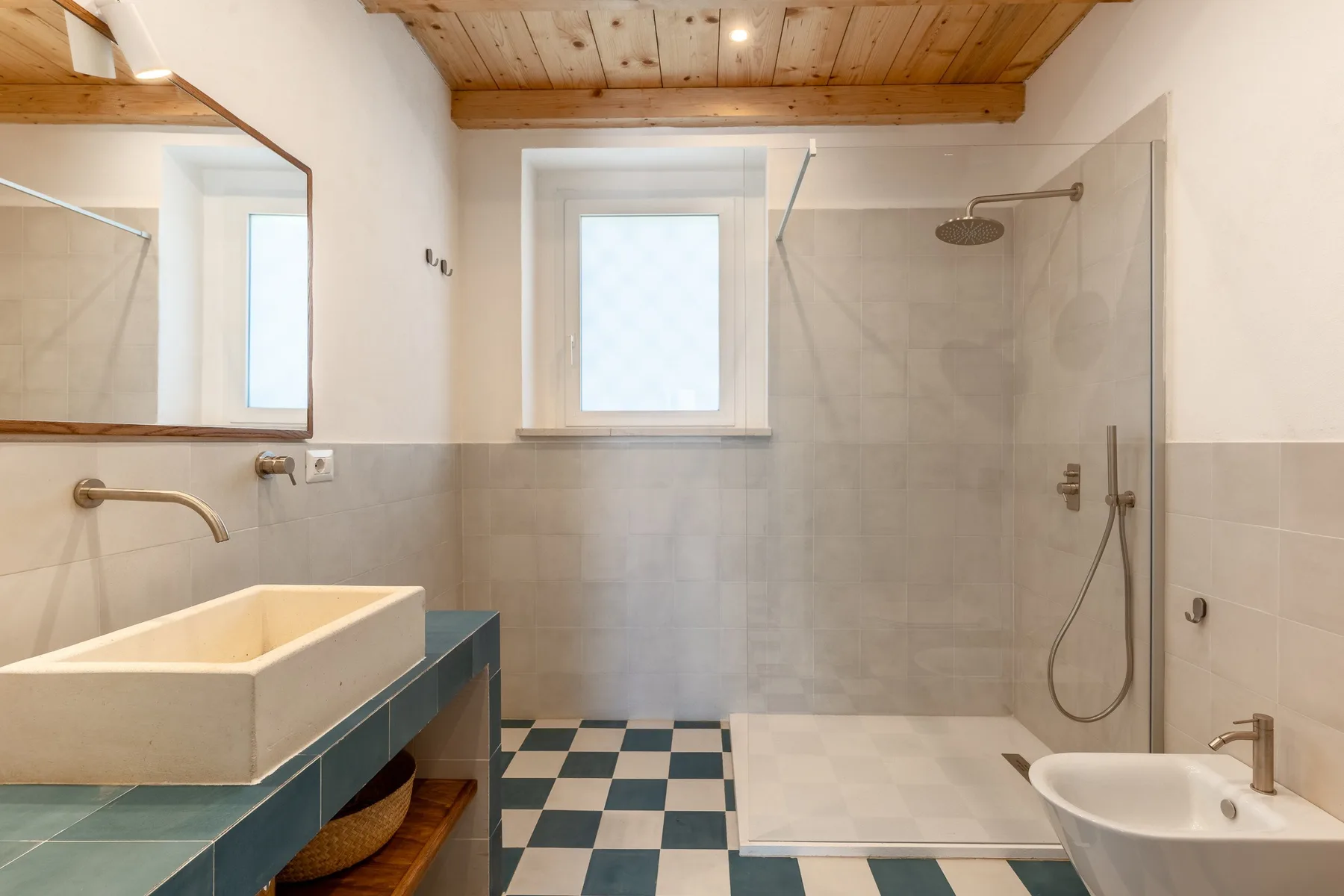 Un baño con ducha alicatada, lavabo y suelo de cuadros.