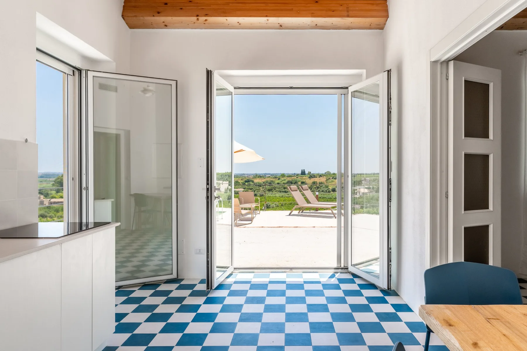 Una habitación luminosa con suelo de baldosas azules y blancas da a una terraza.
