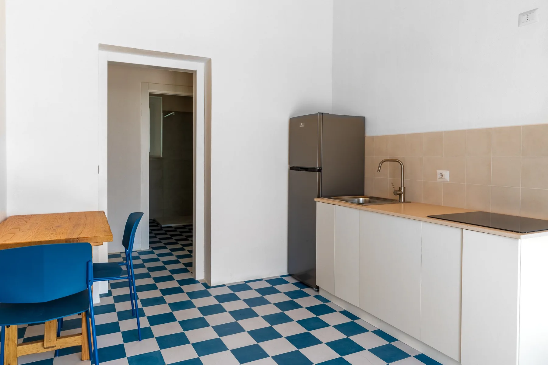 Una cocina con refrigerador, encimera y suelo de cuadros azules y blancos.