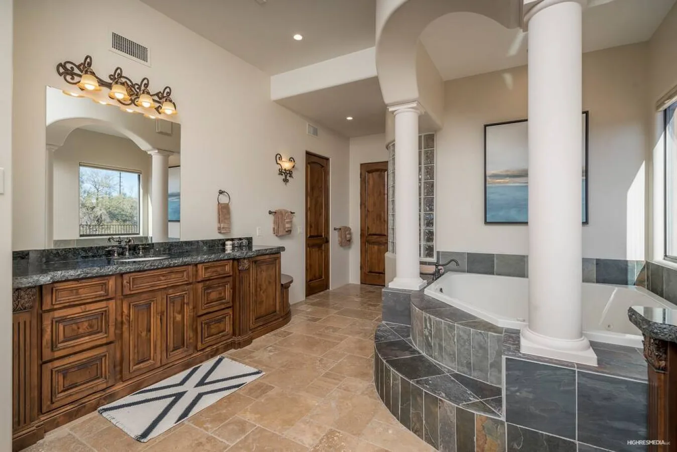 A spacious bathroom features a long wooden vanity and a built-in soaking tub.