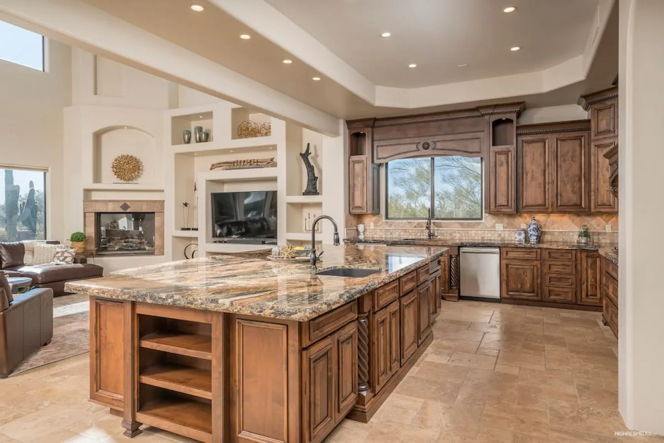 A spacious kitchen features a large island with a stone countertop and wooden cabinets.