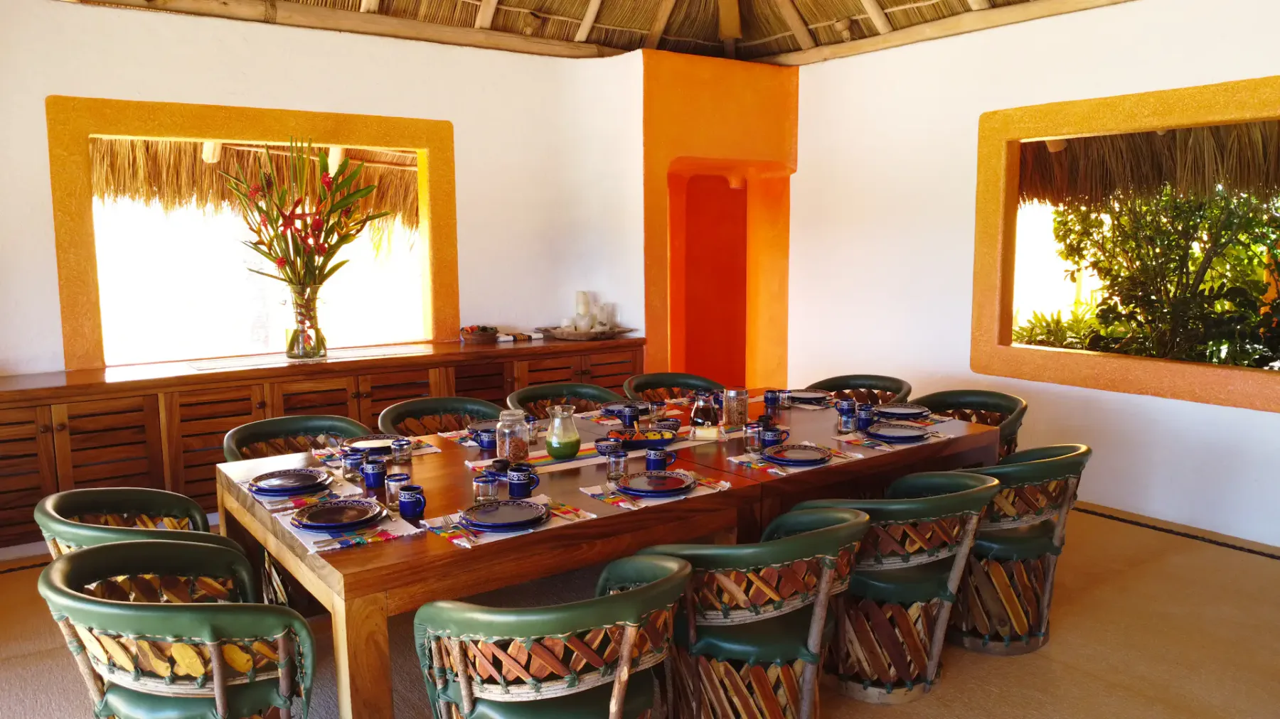 Un comedor con una mesa larga puesta con platos y rodeada de sillas.