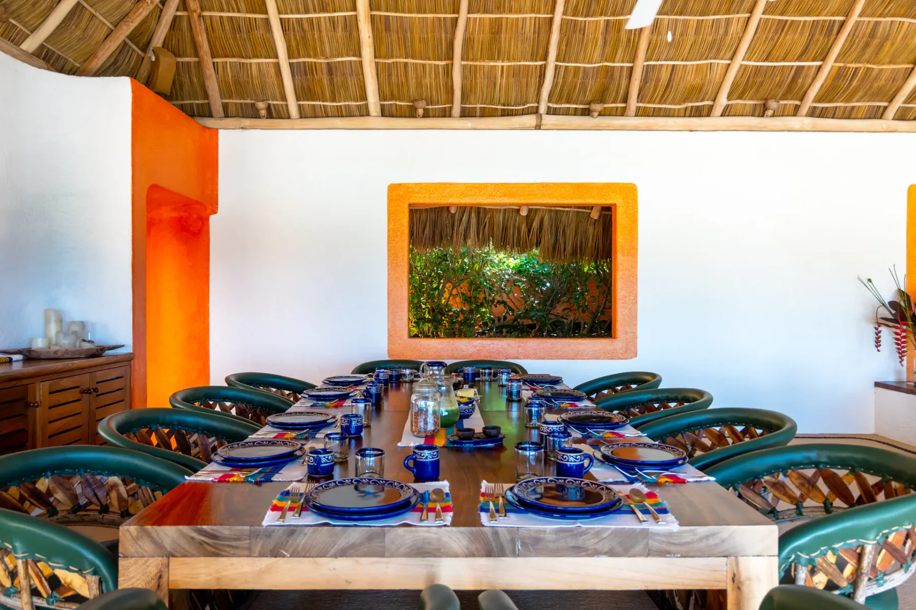 Un comedor con una mesa larga puesta con platos y rodeada de asientos.