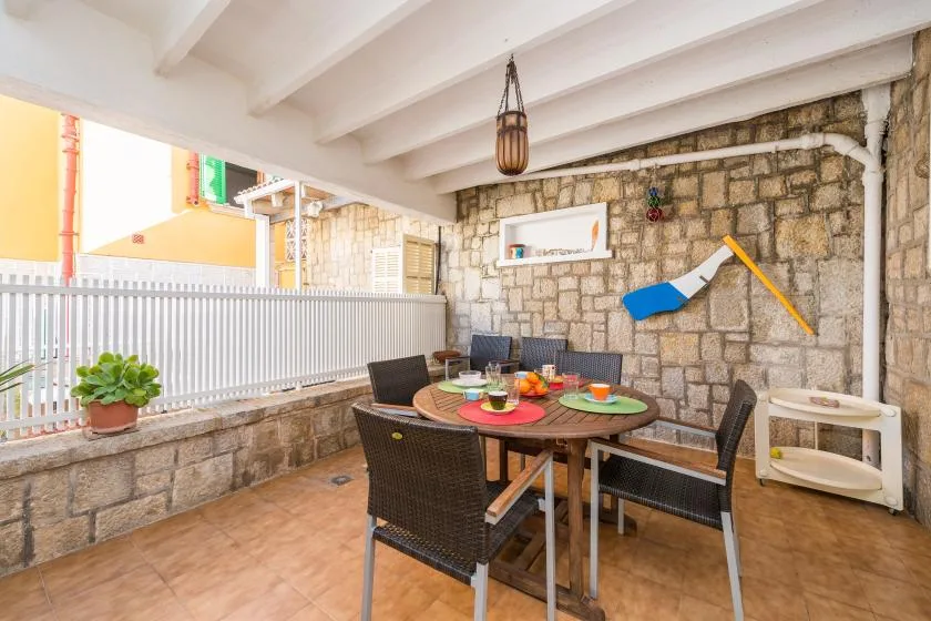 Un comedor cubierto con una mesa y asientos junto a una pared de piedra.