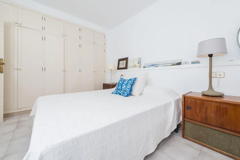 Un dormitorio luminoso con una cama bien hecha y armarios empotrados.
