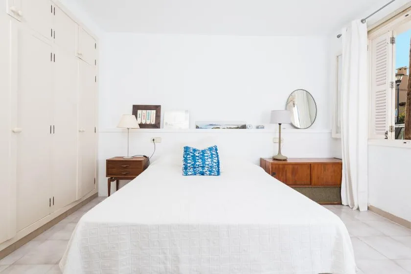 Un dormitorio luminoso con una cama bien tendida y armarios empotrados.